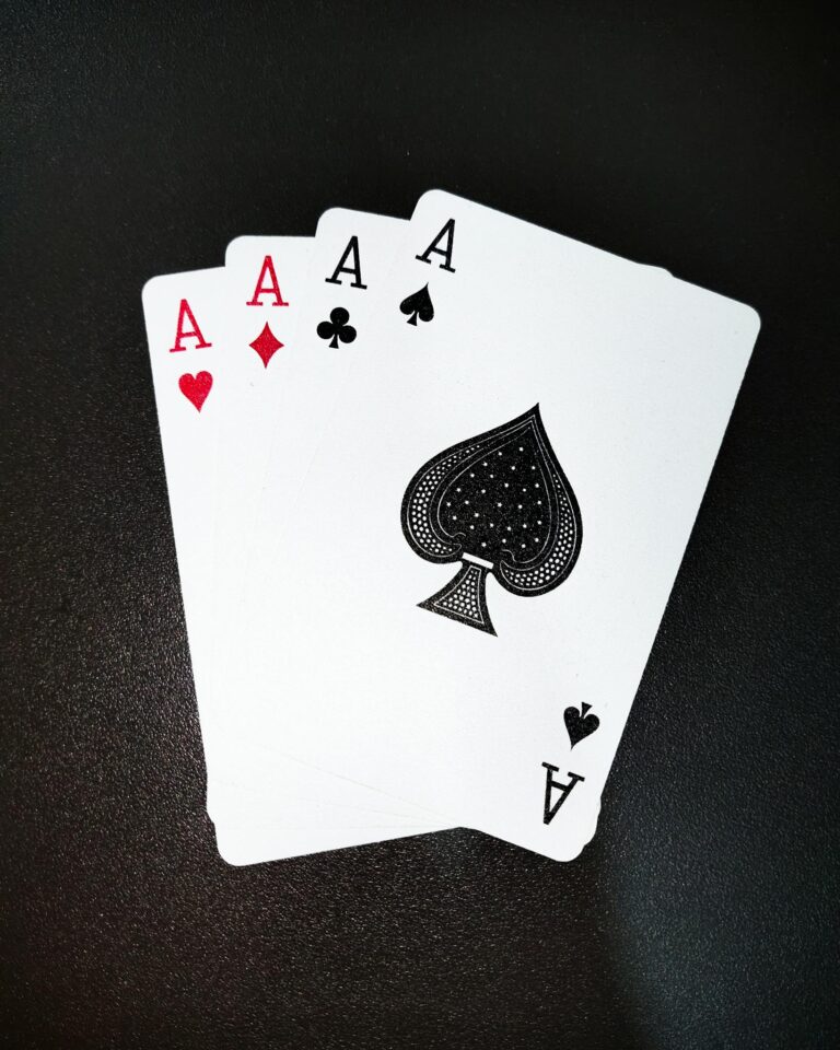 A close-up shot of four aces on a black background, showcasing symbols of poker and gambling.