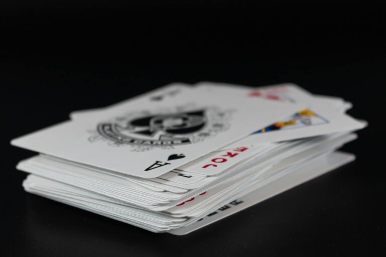 Stack of playing cards with an ace of spades on top, in a dim setting, perfect for games.